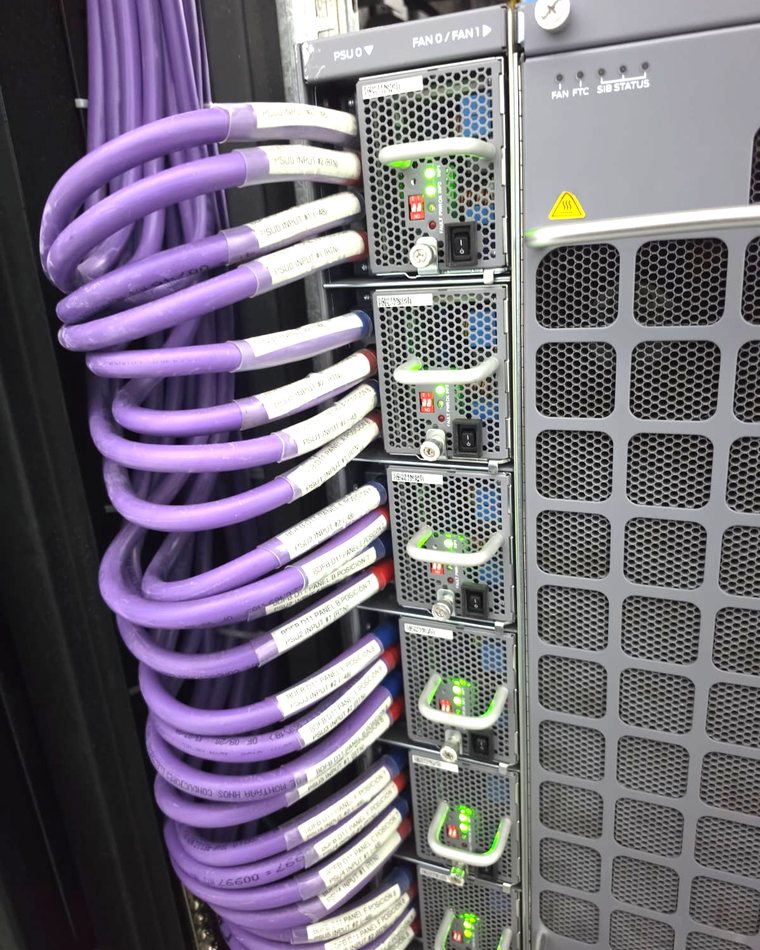 Acometidas de corriente continua en cable multipar violeta, formadas en arco y conectadas a las fuentes de un chasis con sus testigos en verde.